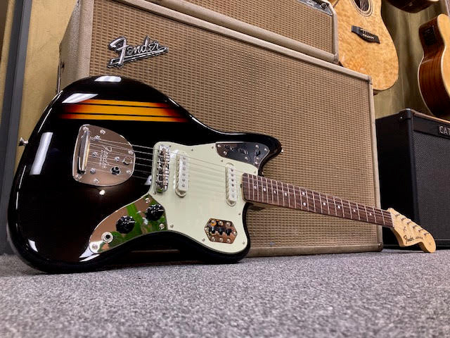 Black electric guitar with a Fender amplifier in the background