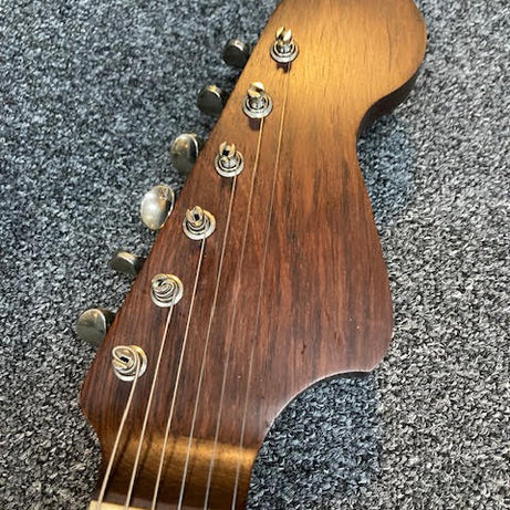 Close-up of a Rosewood headstock with tuning pegs on a textured surface