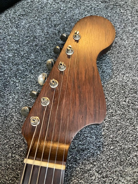 Close-up of a Rosewood headstock with tuning pegs on a textured surface