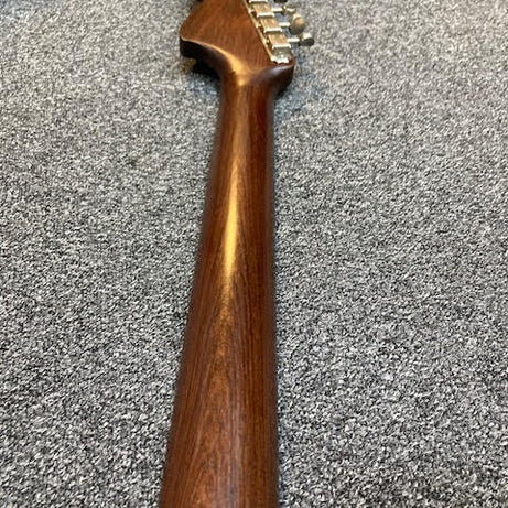 Rosewood guitar neck on a gray surface