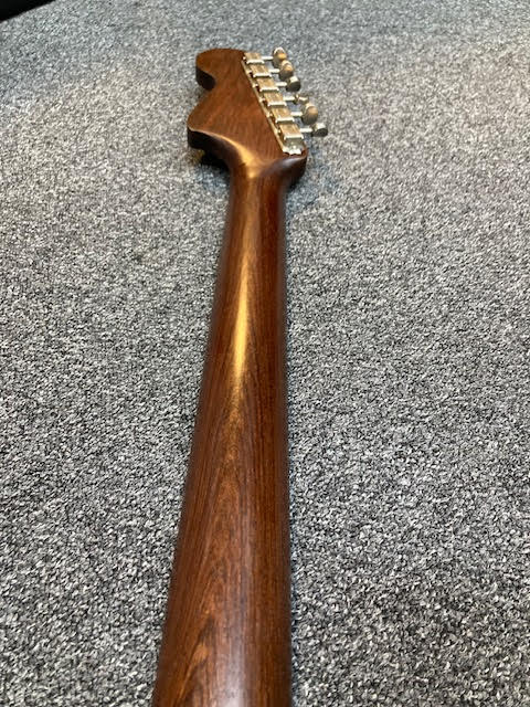 Rosewood guitar neck on a gray surface