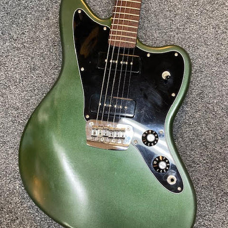 Green Jazzmaster guitar on a grey textured surface