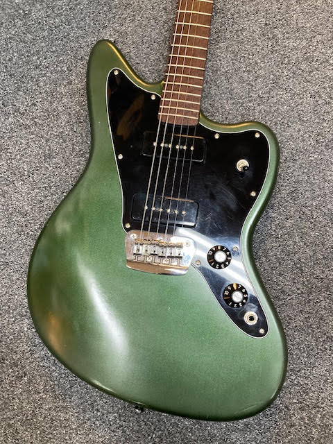Green Jazzmaster guitar on a grey textured surface