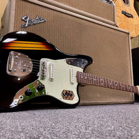 Black electric guitar with a Fender amplifier in the background